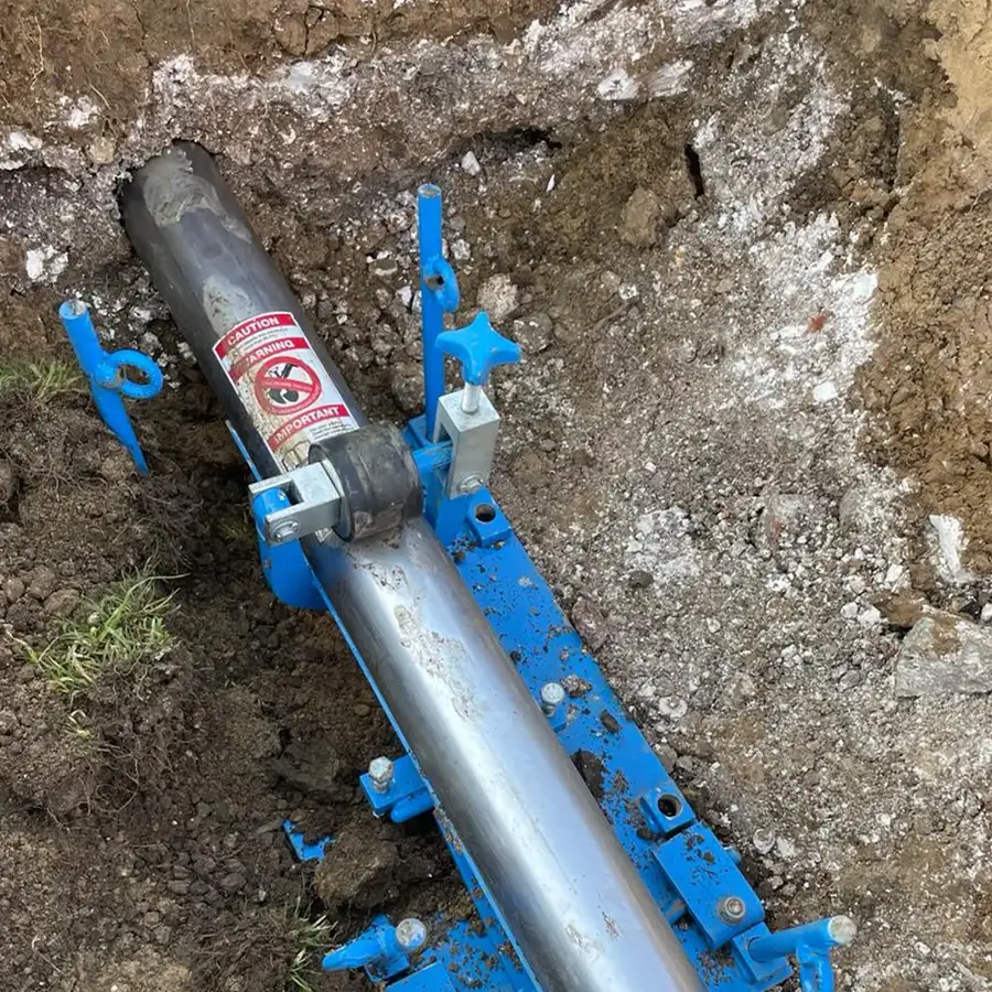 Hydraulic moling tool set up on its launch frame in an excavated pit, ready to drive under the ground