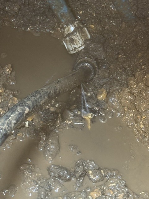 Water leaking from an old supply pipe in a flooded excavation