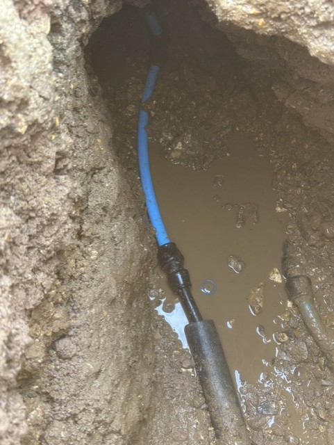 New blue water supply pipe jointed onto the old pipe in an excavation