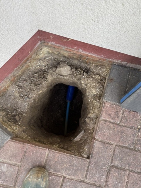 Hole cut through block paving exposing blue supply pipe